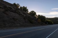 an empty highway with a stop sign in the sunset light behind it and a forest in the distance