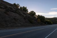 an empty highway with a stop sign in the sunset light behind it and a forest in the distance