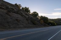 an empty highway with a stop sign in the sunset light behind it and a forest in the distance