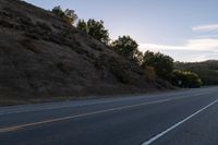 an empty highway with a stop sign in the sunset light behind it and a forest in the distance