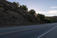 an empty highway with a stop sign in the sunset light behind it and a forest in the distance