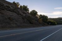 an empty highway with a stop sign in the sunset light behind it and a forest in the distance