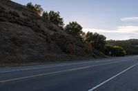 an empty highway with a stop sign in the sunset light behind it and a forest in the distance