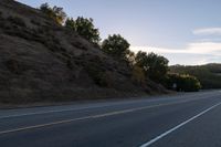 an empty highway with a stop sign in the sunset light behind it and a forest in the distance