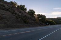 an empty highway with a stop sign in the sunset light behind it and a forest in the distance