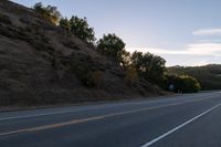 an empty highway with a stop sign in the sunset light behind it and a forest in the distance