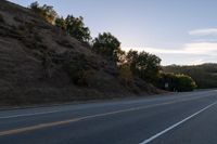 an empty highway with a stop sign in the sunset light behind it and a forest in the distance