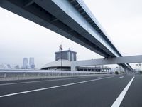 an empty highway has white lines on the side of it and high rise buildings in the background
