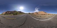 two cars driving down an empty road under a clear blue sky above a desert with the sun shining