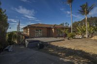 an empty house with lots of windows and landscaping in front of it at the top of the road, palm trees on either side