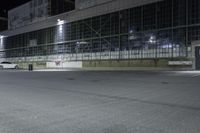 empty industrial building at night time with no windows and lights on the side and a street sign in front of it