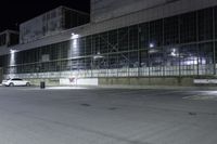 empty industrial building at night time with no windows and lights on the side and a street sign in front of it