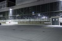 empty industrial building at night time with no windows and lights on the side and a street sign in front of it