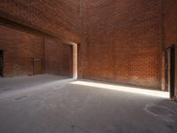 an empty space is filled with red brick walls and windows with a bright beam coming out of the doorway