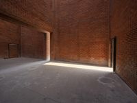 an empty space is filled with red brick walls and windows with a bright beam coming out of the doorway