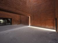 an empty space is filled with red brick walls and windows with a bright beam coming out of the doorway