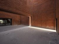 an empty space is filled with red brick walls and windows with a bright beam coming out of the doorway