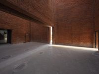 an empty space is filled with red brick walls and windows with a bright beam coming out of the doorway