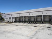 the front of an empty industrial warehouse on a sunny day, with yellow lines all over the concrete surface