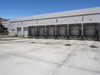 the front of an empty industrial warehouse on a sunny day, with yellow lines all over the concrete surface