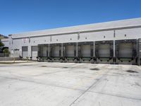 the front of an empty industrial warehouse on a sunny day, with yellow lines all over the concrete surface