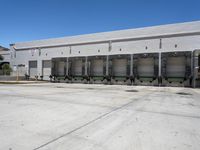 the front of an empty industrial warehouse on a sunny day, with yellow lines all over the concrete surface