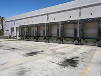 the front of an empty industrial warehouse on a sunny day, with yellow lines all over the concrete surface