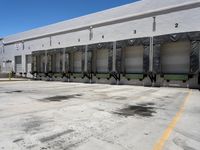 the front of an empty industrial warehouse on a sunny day, with yellow lines all over the concrete surface