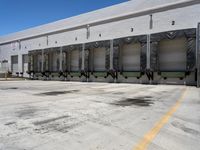 the front of an empty industrial warehouse on a sunny day, with yellow lines all over the concrete surface