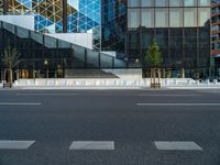 an empty intersection with several empty lounge chairs and trees in front of some building facades