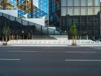 an empty intersection with several empty lounge chairs and trees in front of some building facades