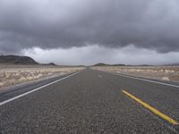 an empty empty long road with yellow strip on the center and dark skies above it