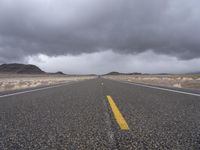 an empty empty long road with yellow strip on the center and dark skies above it