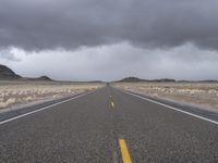 an empty empty long road with yellow strip on the center and dark skies above it