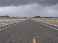 an empty empty long road with yellow strip on the center and dark skies above it