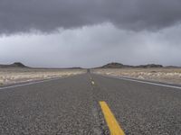 an empty empty long road with yellow strip on the center and dark skies above it