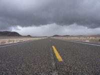 an empty empty long road with yellow strip on the center and dark skies above it