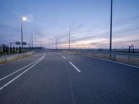 a highway stretches to a sky lined with street lights and poles at night in an empty lot