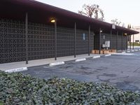 an empty parking lot with benches and plants on the side of it and buildings behind