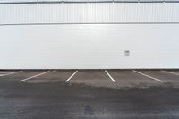 the parking lot is empty in front of an industrial building where two people are standing