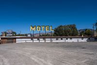 the old motel sign sits empty on a street in front of a building with an open parking lot