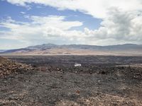 the view from an empty mountain looking out to a barren plain with mountains in the distance