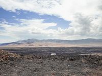 the view from an empty mountain looking out to a barren plain with mountains in the distance