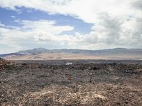 the view from an empty mountain looking out to a barren plain with mountains in the distance