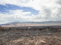 the view from an empty mountain looking out to a barren plain with mountains in the distance