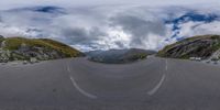 a fish - eye lens view shows an empty mountain road with steep, steep cliffs