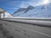 the snow covered mountains are in the distance as an empty mountain road passes under a bridge