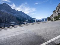 an empty street near the mountains with a railing on one side and a sign that reads al