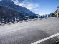 an empty street near the mountains with a railing on one side and a sign that reads al