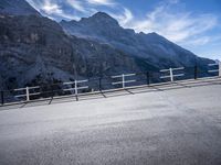 an empty street near the mountains with a railing on one side and a sign that reads al